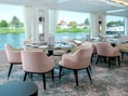 Elegantes Restaurant mit rosa Stühlen und Flussblick.