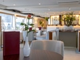 Elegantes Restaurantinterieur mit einem Tisch, einer Rose und Speisekarte in Vordergrund.