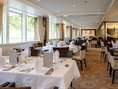 Elegantes Restaurant mit gedeckten Tischen und grossen Fenstern.