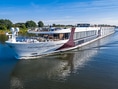 Flusskreuzfahrtschiff auf einem Fluss mit klarem Himmel.