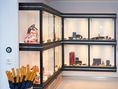 Luxus-Accessoires in Glasvitrine mit Regenschirmständer im Vordergrund.