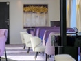 Innenraum eines Restaurants mit lila und weissen Stühlen.