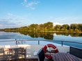 Blick von einem Boot auf ruhigen Fluss und bewaldetes Ufer.
