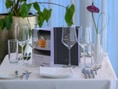 Elegantes Gedeck mit Weingläsern und Besteck auf einem Tisch, dekoriert mit einer Pflanze.