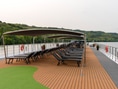 Oberdeck eines Flusskreuzfahrtschiffs mit Liegestühlen und Markise.