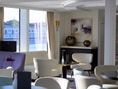 Eleganter Loungebereich mit Sesseln und grossen Fenstern.