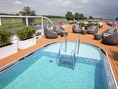 Deck eines Kreuzfahrtschiffs mit Pool und Sitzbereichen.