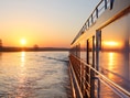 Bootsfahrt auf Fluss bei Sonnenuntergang.