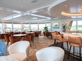 Elegante Lounge mit Tischen, Stühlen und Bar.