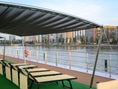 Deck eines Schiffes mit Liegestühlen am Flussufer.