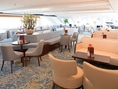 Elegante Lounge mit Tischen und Sesseln auf einem Kreuzfahrtschiff.