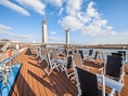Sonnendeck eines Schiffes mit Stühlen und Blick auf eine Hebebrücke.
