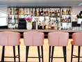Moderne Bar mit rosa Hockern und Flaschenregal.