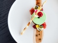 Gourmet-Dessert mit grünem Mousse und Früchten auf Teller.