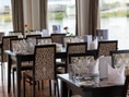 Elegantes Restaurant mit gedeckten Tischen am Wasser.