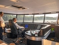 Zwei Männer im Schiffssteuerhaus mit Flussblick.