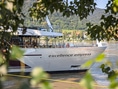 Kreuzfahrtschiff Excellence Empress auf einem Fluss, umgeben von Bäumen.