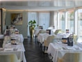 Elegantes Restaurant mit weiss gedeckten Tischen und Blick auf das Wasser.