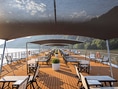 Deck eines Flusskreuzfahrtschiffs mit Sonnendächern und Liegestühlen.