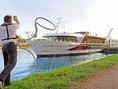 Mann wirft Seil zu Kreuzfahrtschiff Excellence Queen am Fluss.