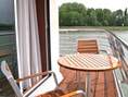 Holztisch und Stühle auf einem Flusskreuzfahrtschiffdeck.