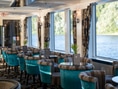 Elegantes Restaurant mit Flussblick und blauen Polstersesseln.