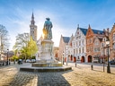 Platz mit Statue und historischen Gebäuden im Hintergrund.