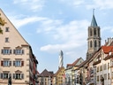 Strassenszene in einer europäischen Altstadt mit Kirchturm.