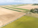 Luftaufnahme von weitläufigen Feldern und Küstenlandschaft.