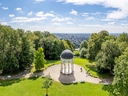 Blick auf Kuppelbau in grüner Parklandschaft.
