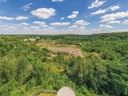 Landschaftsansicht mit bewaldeten Hügeln unter blauem Himmel.