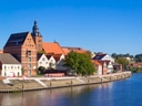 Historische Gebäude am Flussufer mit blauem Himmel.