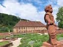 Steinfigur in einem Schlossgarten mit Gebäude im Hintergrund.