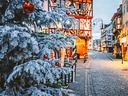Verschneiter Weihnachtsbaum in festlich dekorierter Altstadtstrasse.