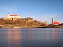 Blick auf Schloss und Kirche am Flussufer bei blauem Himmel.