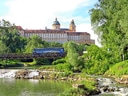 Majestätisches Gebäude hinter bewaldetem Fluss und Brücke.