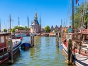 Hafen mit historischen Booten und Turm im Hintergrund.