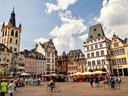 Menschen auf belebtem Platz mit historischen Gebäuden.