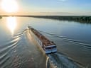 Grosses Kreuzfahrtschiff auf einem Fluss bei Sonnenuntergang.