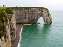 Felsenküste von Étretat mit Felsbogen und Meer.