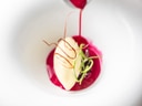 Rote Sauce wird auf Dessert in weissem Teller gegossen.