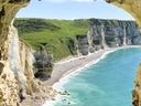 Blick aus einer Höhle auf eine Küste mit Klippen und blauem Meer.