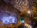 Weihnachtslichter und Menschen in einer beleuchteten Höhle.