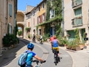 Gruppe von Radfahrern in enger, sonniger Altstadtstrasse.
