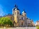Historische Kirche mit Türmen auf sonnigem Platz.