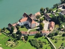 Luftaufnahme eines Schlosses am Fluss mit umliegenden Gebäuden und Gärten.