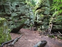 Person in waldreicher Felsschlucht mit Moos und Laub.