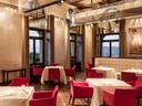 Elegantes Restaurantinterieur mit roten Stühlen, gedeckten Tischen und kunstvoller Decke.