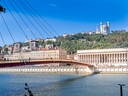 Fluss in Lyon mit Brücke und Hügel im Hintergrund.
