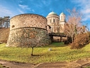 Panorama der Esztergom-Basilika mit Burgmauer und Bäumen.